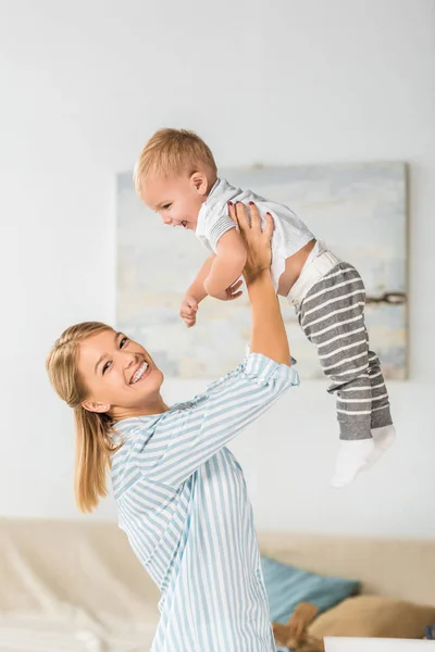 Fröhliche Mutter Blickt Die Kamera Und Hält Lächelndes Kleinkind Den — Stockfoto