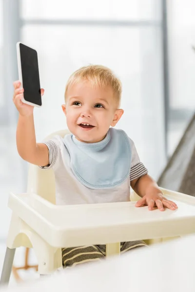 Niedlich Lächelndes Kleinkind Mit Smartphone Der Hand Und Kinderstuhl Sitzend — Stockfoto