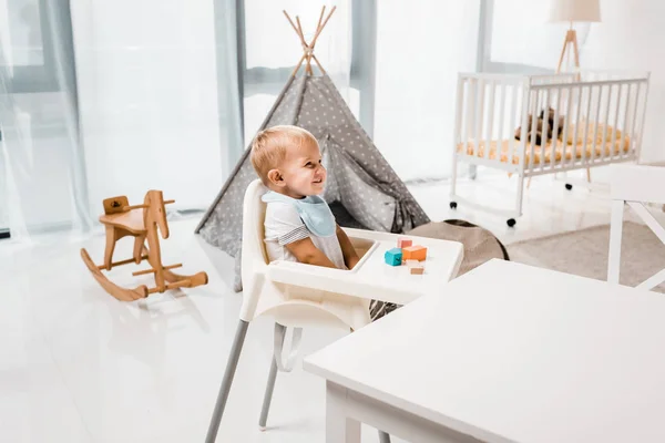 赤ちゃんグッズ キューブと保育室で椅子に座って幸せな幼児 — ストック写真