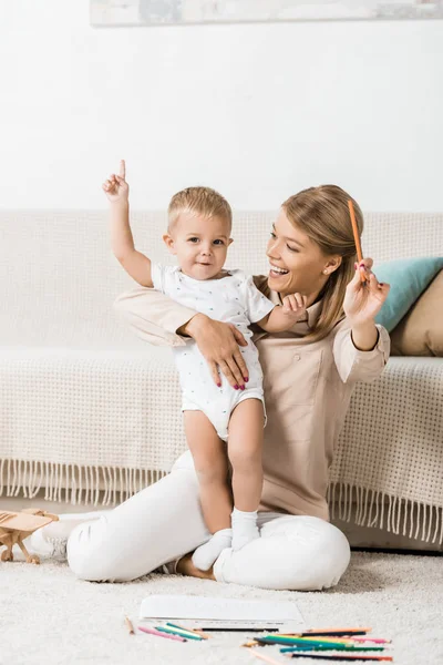 Feliz Madre Adorable Niño Mirando Cámara Sosteniendo Lápices Habitación Guardería —  Fotos de Stock