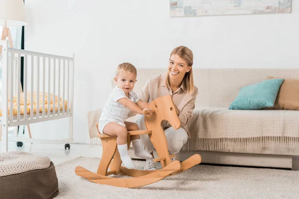 Adorable Toddler Sitting Toy Wooden Horse Looking Camera Smiling Mother — Stock Photo, Image