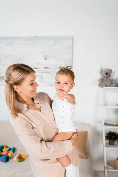 Sonriente Madre Sosteniendo Adorable Niño Apuntando Cámara —  Fotos de Stock