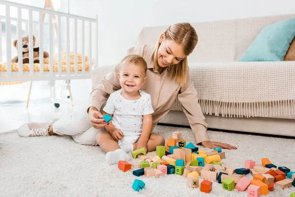 可爱的幼儿玩五颜六色的立方体和母亲在托儿所室 — 图库照片