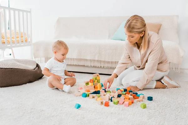 カラフルなキューブと保育室で母と遊ぶ愛らしい幼児 — ストック写真