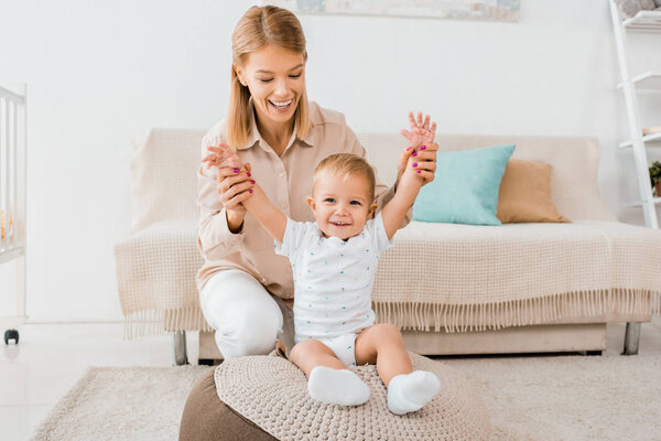 adorable toddler raising hands up with mother in nursery room