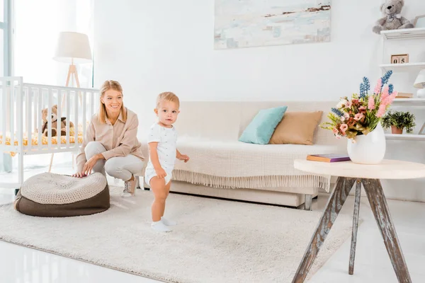 Schattig Peuter Kijken Camera Kwekerij Kamer Met Moeder Achtergrond — Stockfoto