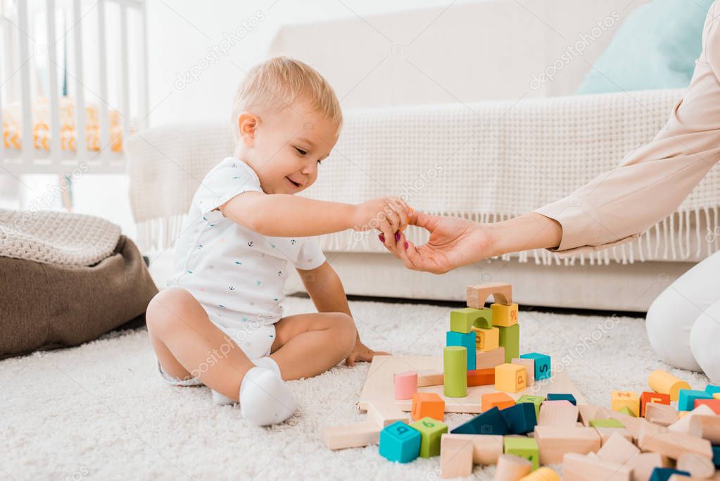 adorable toddler playing with colorful cubes in nursery room