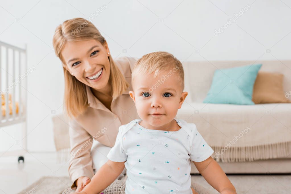 adorable toddler looking at camera with mother in nursery room