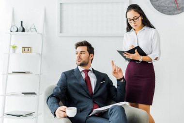 Asya iş kadını ofiste işadamı oturan ve sahip kahve molası sırasında not defterinizdeki yazma