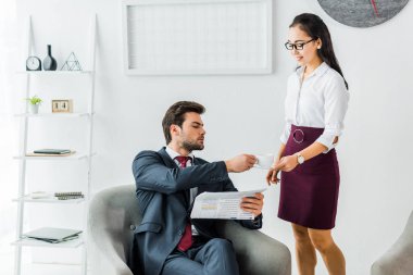 Office Asya işkadını kahve fincanı alarak gazete ile işadamı