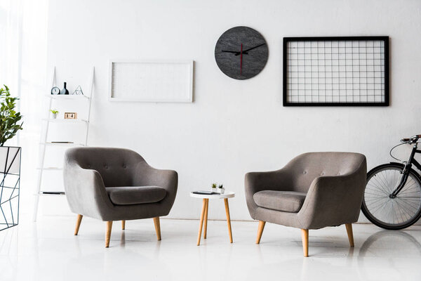 современный интерьер зала ожидания с серыми креслами и столом
