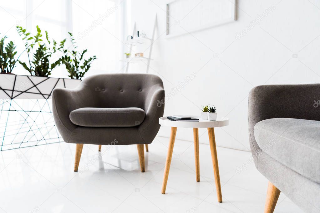 modern interior of white waiting hall with grey armchairs and table