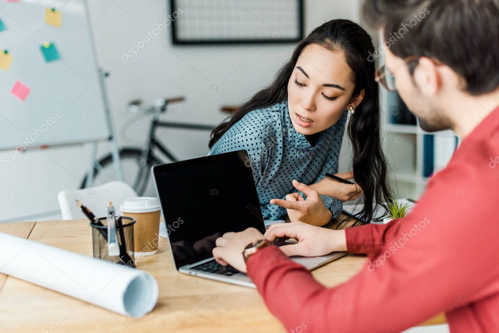Couple of architects using laptop with blank screen in office