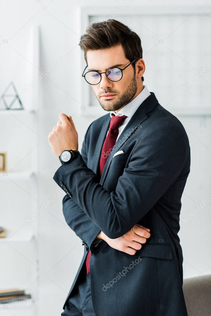 serious handsome businessman in formal wear and glasses in office