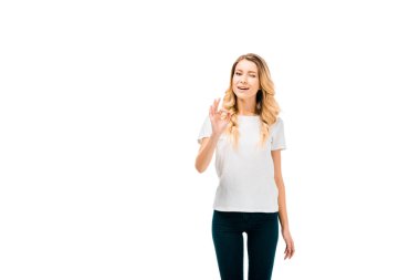 ok işaret gösteren ve üzerinde beyaz izole kamera göz kırpıyor güzel genç kadın