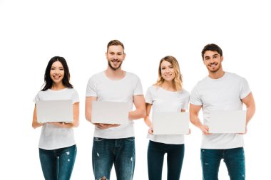 mutlu genç erkek ve kadınların beyaz dizüstü bilgisayarlar tutarak ve kameraya gülümseyen t-shirt üzerinde beyaz izole