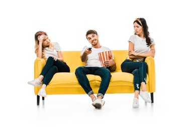 patlamış mısır kutusu ve bıkkın ve üzgün kadın üzerinde beyaz izole kanepede oturuyordu süre tarassut tv uzaktan kumanda ile gülümseyen genç adam