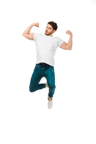 handsome man in white t-shirt jumping and showing muscles isolated on white