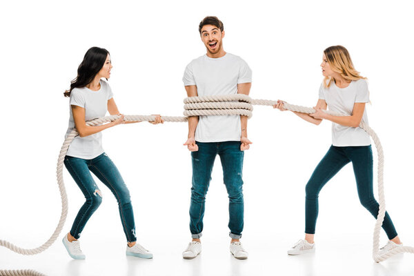 emotional young women holding rope around young man smiling at camera isolated on white 