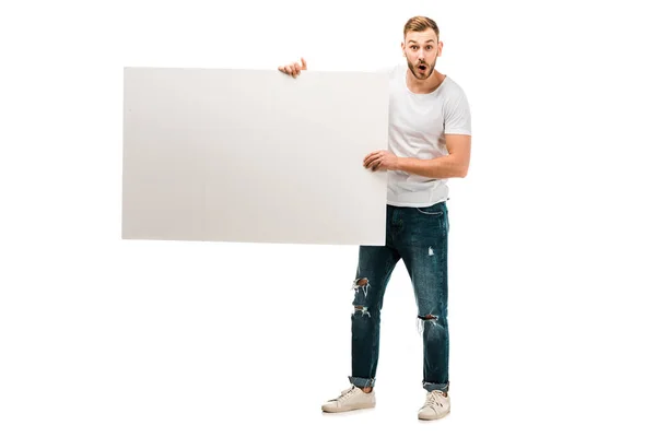 Шокований Молодий Чоловік Тримає Порожній Плакат Дивиться Камеру Ізольовано Білому — стокове фото