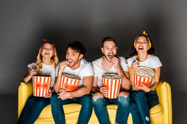 Jovens Amigos Alegres Sentados Sofá Amarelo Assistindo Filme Comendo Pipocas — Fotografia de Stock