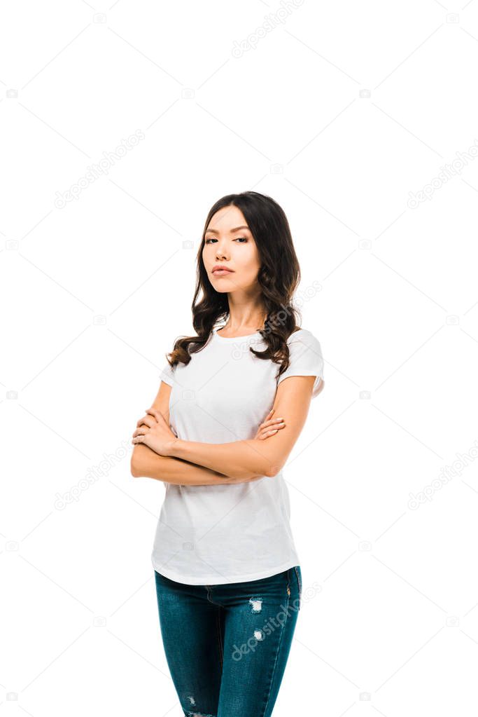 confident young woman standing with crossed arms and looking at camera isolated on white