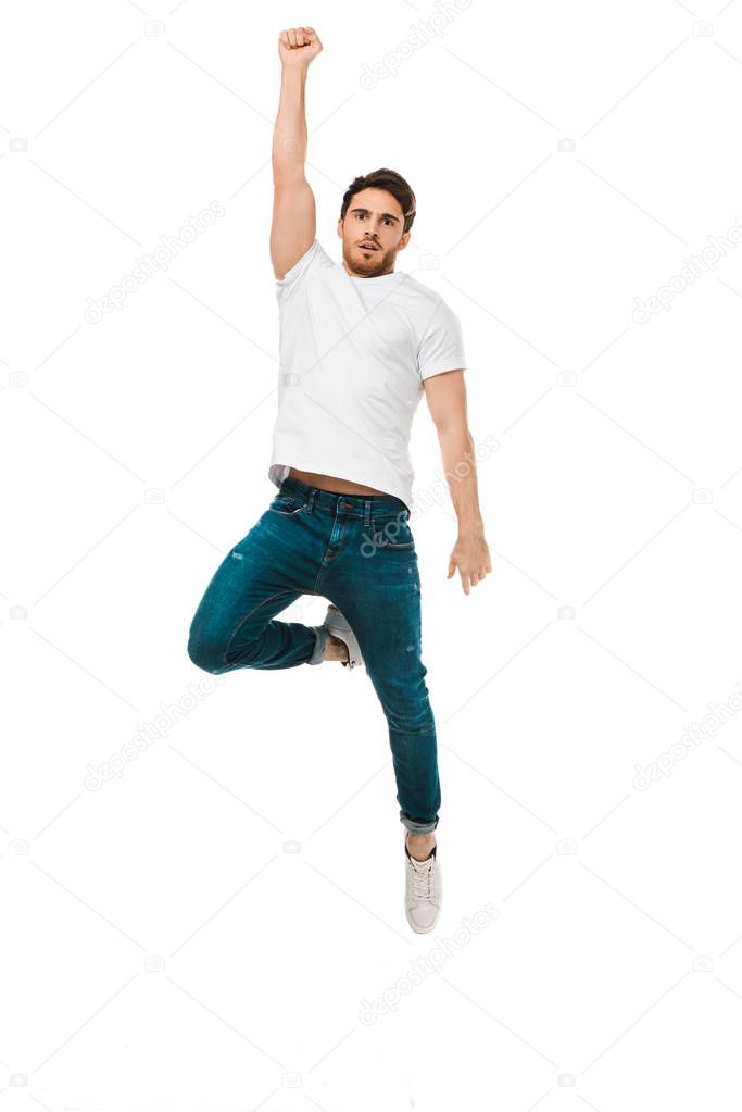 serious handsome man jumping with raised hand and looking at camera isolated on white