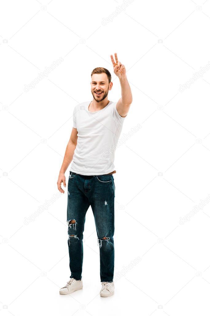 full length view of handsome happy man showing victory sign and looking at camera isolated on white