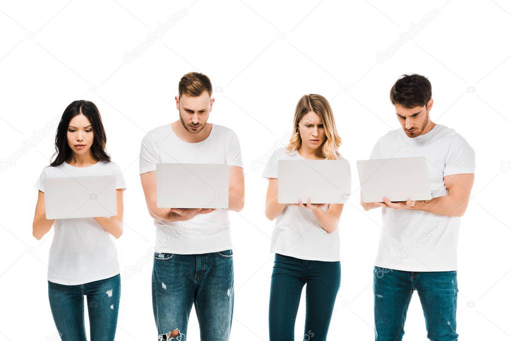 focused young people in white t-shirts using laptops isolated on white