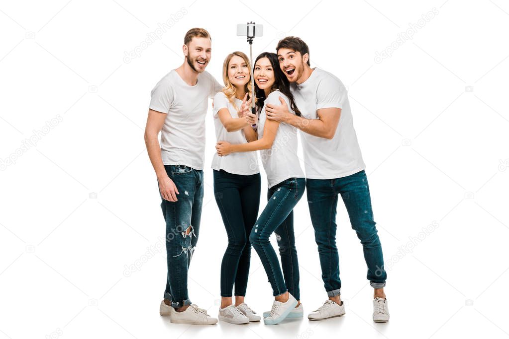 happy young friends taking selfie with smartphone and selfie stick isolated on white