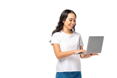 Gülümseyen genç görüntülü sohbet kadın beyaz t-shirt ve kot üzerinde beyaz izole dizüstü bilgisayar kullanarak