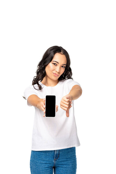 Dissatisfied asian woman holding smartphone with blank screen and showing thumb down isolated on white