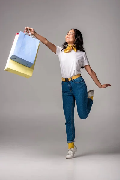 Gelukkig Aziatische Vrouw Houdt Van Kleurrijke Boodschappentassen Gestrekte Hand Grijs — Stockfoto