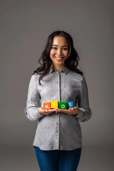 単語の子供たちとアルファベット キューブをグレーにつかまって陽気な妊娠中の若いアジア女性 — ストック写真