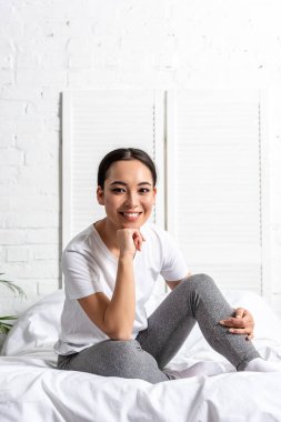 mutlu Genç Asyalı kadın yatakta oturuyor ve sabah egzersiz sonra dinlenme