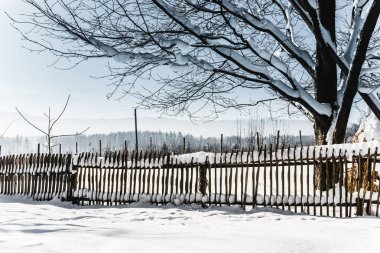 wooden fence covered with snow in carpathian mountains clipart