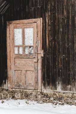 old weathered wooden house with door in winter clipart