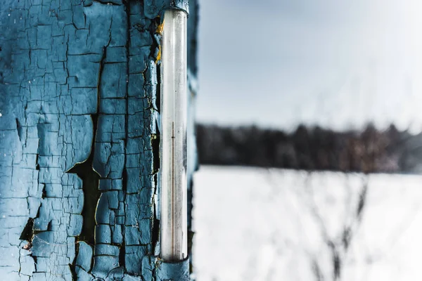 selective focus of thermometer in weathered old blue board in winter