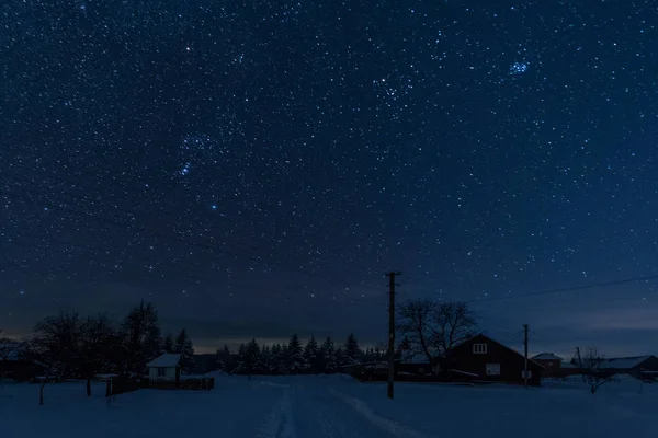 星空在山上被雪覆盖的村庄之上 — 图库照片