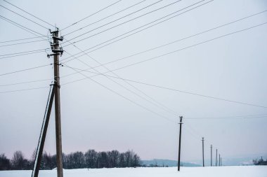 electric poles with wires in field covered with snow clipart