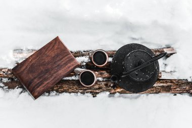 günlüklerindeki kar arasında su ısıtıcısı, çay ve tahta kutu ile bardak Üstten Görünüm