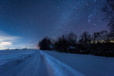 yıldızlı karanlık gökyüzü ve Karpat Dağları'nda kışın geceleri karlı yol