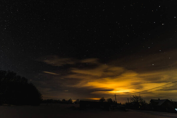 звездное темное небо и желтый свет в Карпатах ночью зимой
