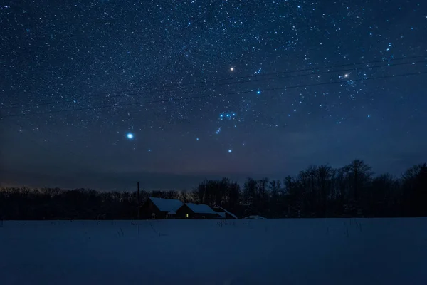 starry dark sky and house in carpathian mountains at night in winter