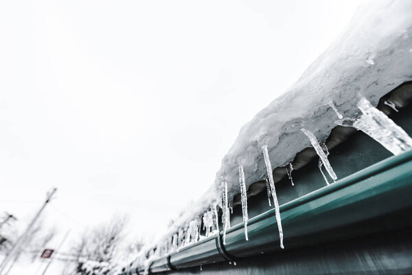 selective focus of sharp icicles on roof against clear sky