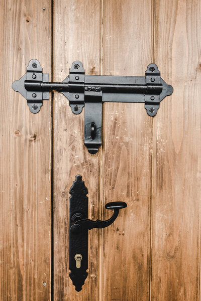 black ironshod lock and handle on wooden beige textured door