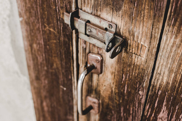 close up of wooden weathered door with rusty handle and lock
