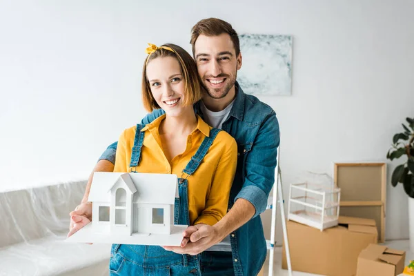 Sonriente Pareja Sosteniendo Casa Juguete Mirando Cámara Casa —  Fotos de Stock