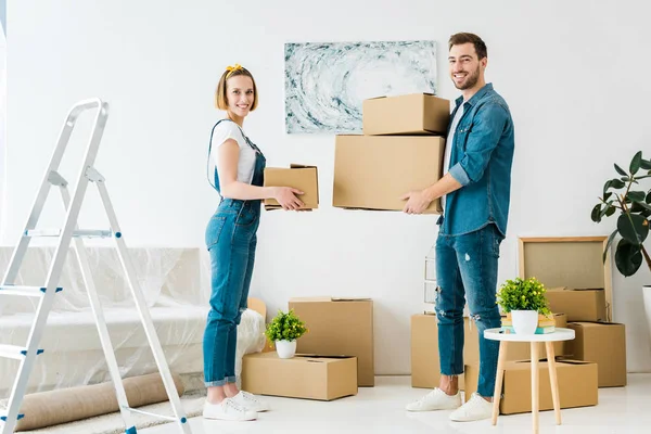 Vista Completa Pareja Sonriente Sosteniendo Cajas Cartón Mirando Cámara — Foto de Stock