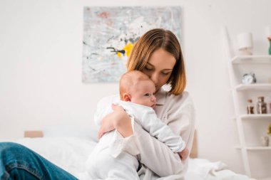 Evde bebek tutan beyaz gömlekli mutlu anne